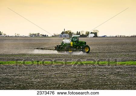 Stock Photograph - Agriculture - Applying pre-emergent herbicide with a John Deere 4720 sprayer to a newly planted soybean field with the purpose of decreasing weed pressure while optimizing yield potential / Central Iowa, USA.. Fotosearch