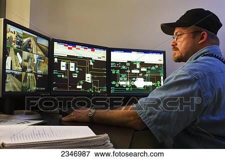 Stock Photo - Agriculture - Ethanol production plant. A worker observing computer LCD screens that monitor the operations throughout the plant / Iowa, USA.. Fotosearch