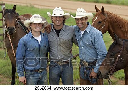 Picture - Agriculture - Three smiling cowboys pose with their horses after a day of work / Childress, Texas, USA.. Fotosearch