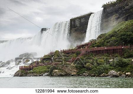 Picture - American Falls and tourists in yellow raincoats climbing the walkway; Niagara Falls, New York, USA. Fotosearch