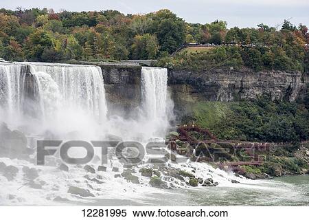 Stock Photography - American Falls and tourists in yellow raincoats climbing the walkway; Niagara Falls, New York, USA. Fotosearch