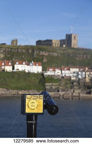 Binoculars with coin slot at the water's edge with a view of buildings on the hillside; Whitby, North Yorkshire, England View Large Photo Image Stock Photography - Binoculars with coin slot at the water's edge with a view of buildings on the hillside; Whitby, North Yorkshire, England. Fotosearch