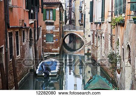 Boats moored in a tranquil canal between buildings; Venice, Italy View Large Photo Image Stock Image - Boats moored in a tranquil canal between buildings; Venice, Italy. Fotosearch