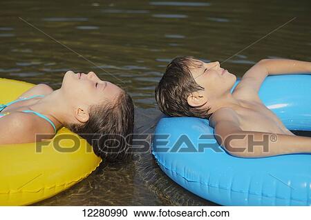 Boy and girl floating with inflatable rings on Crystal Lake; Ontario, Canada View Large Photo Image Stock Image - Boy and girl floating with inflatable rings on Crystal Lake; Ontario, Canada. Fotosearch
