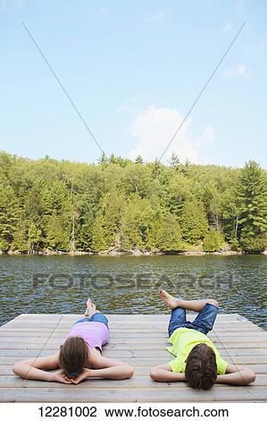 Stock Image - Boy laying down on dock; Ontario, Canada. Fotosearch