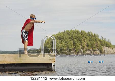 Boy standing on dock wearing goggles and towel pretending to be a super hero; Ontario, Canada View Large Photo Image Stock Image - Boy standing on dock wearing goggles and towel pretending to be a super hero; Ontario, Canada. Fotosearch