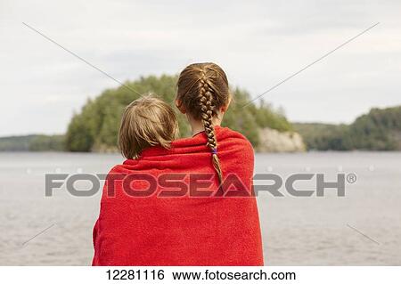 Stock Photograph - Brother and sister wrapped in towel standing in Mara lake; Ontario, Canada. Fotosearch