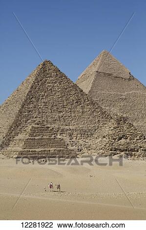 Stock Image - Camels with tourist and guide, Queen's Pyramid and Pyramid of Chephren (background), The Giza Pyramids; Giza, Egypt. Fotosearch