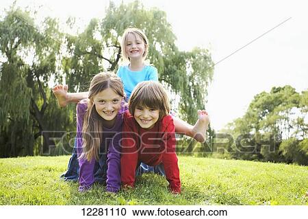 Stock Image - Children in a park making a human pyramid; Toronto, Ontario, Canada. Fotosearch