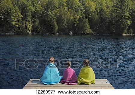 Children wrapped in towels sitting at end of dock on Crystal Lake; Ontario, Canada View Large Photo Image Stock Photo - Children wrapped in towels sitting at end of dock on Crystal Lake; Ontario, Canada. Fotosearch