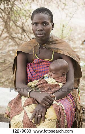 Datoga mother wearing traditional clothing holds baby on her lap near Lake Eyasi; Tanzania View Large Photo Image Stock Image - Datoga mother wearing traditional clothing holds baby on her lap near Lake Eyasi; Tanzania. Fotosearch
