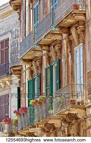 Stock Photograph - Facade of a residential building with shutters and balconies; Syracuse, Sicily, Ortigia, Italy. Fotosearch