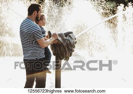Stock Photograph - Father and young son at spray park; Edmonton, Alberta, Canada. Fotosearch
