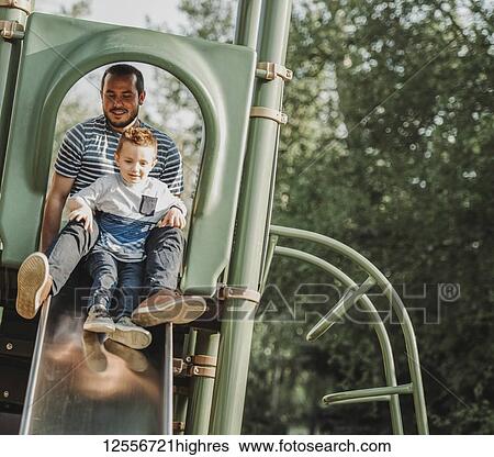 Stock Photograph - Father on a slide with young son; Edmonton, Alberta, Canada. Fotosearch