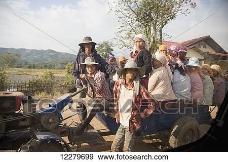 Stock Photo - Female road construction workers wait to be carried by cart and tractor to their work site; Myanmar. Fotosearch