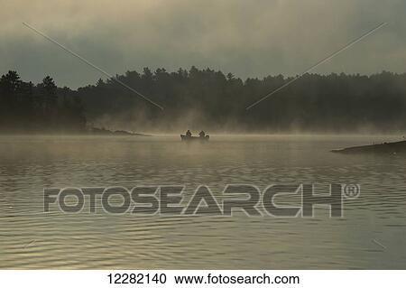 Stock Image - Fishing in the early morning fog; Ontario, Canada. Fotosearch