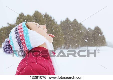 Stock Photograph - Girl catching snowflakes on her tongue; King City, Ontario, Canada. Fotosearch
