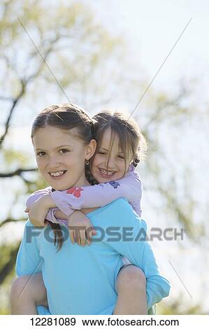 Girl giving younger sister a piggy back ride; Toronto, Ontario, Canada View Large Photo Image Stock Photo - Girl giving younger sister a piggy back ride; Toronto, Ontario, Canada. Fotosearch