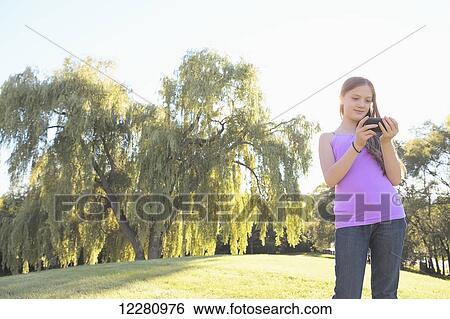 Stock Photograph - Girl outside using smart phone; Toronto, Ontario, Canada. Fotosearch