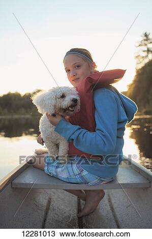Stock Image - Girl sitting in a canoe with her dog on Crystal Lake; Ontario, Canada. Fotosearch