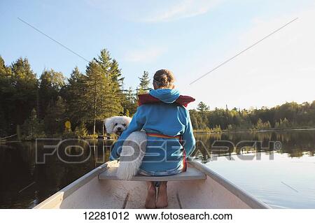Stock Image - Girl sitting in a canoe with her dog; Ontario, Canada. Fotosearch