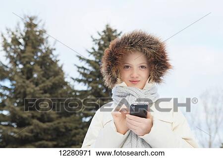 Stock Image - Girl texting on smart phone outdoors in winter; Toronto, Ontario, Canada. Fotosearch