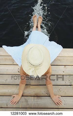 Girl wearing straw hat sitting on end of dock with feet in water; Ontario, Canada View Large Photo Image Stock Image - Girl wearing straw hat sitting on end of dock with feet in water; Ontario, Canada. Fotosearch