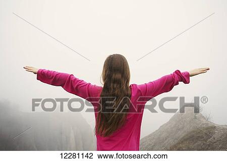 Stock Image - Girl with arms outstreched looking out over Scarborough Bluffs; Toronto, Ontario, Canada. Fotosearch
