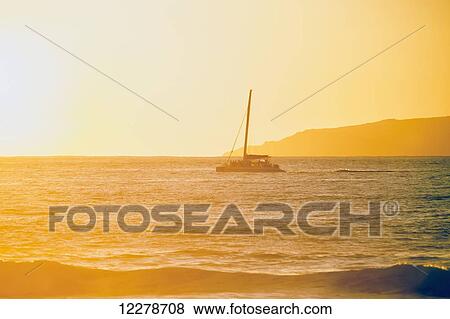 Stock Photo - Golden surf visible from Barking Sands Beach with catamaran crossing the channel; Kekaha, Kauai, Hawaii, United States of America. Fotosearch
