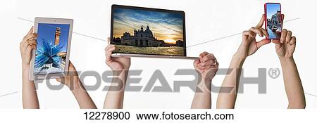 Stock Image - Hands holding tablet, laptop and cell phone in the air above their heads on white background; Sherwood Park, Alberta, Canada. Fotosearch