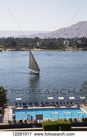 Hotel swimming pool (foreground), Felucca on the Nile River; Luxor, Egypt View Large Photo Image Stock Photo - Hotel swimming pool (foreground), Felucca on the Nile River; Luxor, Egypt. Fotosearch