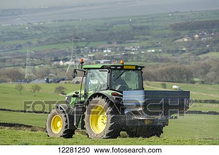 Stock Image - John Deere 6126r spreading fertilizer on upland pasture; Lancashire, England. Fotosearch
