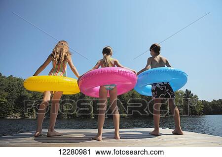 Kids standing at end of dock holding inflatable rings on Crystal Lake; Ontario, Canada View Large Photo Image Stock Image - Kids standing at end of dock holding inflatable rings on Crystal Lake; Ontario, Canada. Fotosearch
