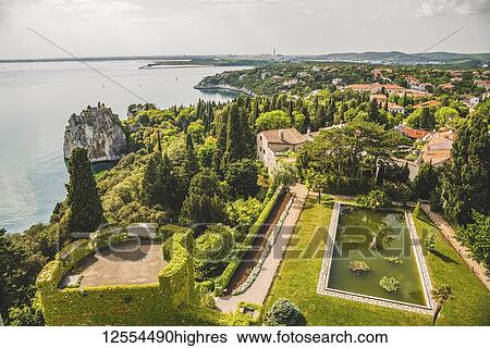 Stock Photograph - Landscaped grounds of Duino Castle and a view of the coastline of the Gulf of Trieste; Italy. Fotosearch