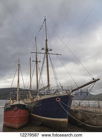 Large sailboats with masts mooring along a pier under a cloudy sky; Scotland View Large Photo Image Stock Photo - Large sailboats with masts mooring along a pier under a cloudy sky; Scotland. Fotosearch