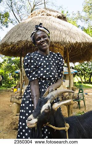 Picture - Livestock - An African woman poses with a goat in her village / Kenya, Africa.. Fotosearch