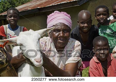 Stock Photo - Livestock - Close up of elderly African woman and children holding a goat outside a building in their village / Kenya, Africa.. Fotosearch
