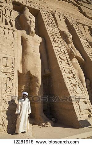 Local man at temple entrance, Ramses II statue (left), Queen Nefetari statue (right), Hathor Temple of Queen Nefertari, Abu Simbel temples; Nubia, Egypt View Large Photo Image Stock Photo - Local man at temple entrance, Ramses II statue (left), Queen Nefetari statue (right), Hathor Temple of Queen Nefertari, Abu Simbel temples; Nubia, Egypt. Fotosearch