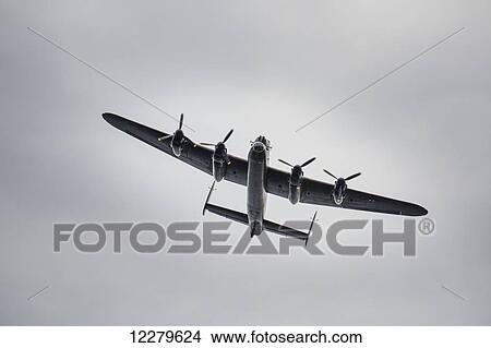 Picture - Low angle view of a plane in a sky with clouds; Sunderland, Tyne and Wear, England. Fotosearch