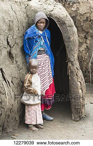 Maasai mother and child stand at entrance to traditional mud hut, Ngorongoro Conservation Area; Tanzania View Large Photo Image Stock Photo - Maasai mother and child stand at entrance to traditional mud hut, Ngorongoro Conservation Area; Tanzania. Fotosearch