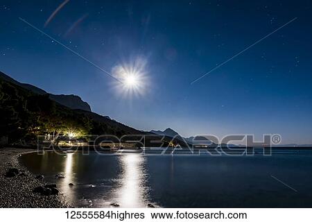Stock Photograph - Makarska Riviera at night with the bright moonlight casting light on the tranquil water along the coastline; Dalmatia, Croatia. Fotosearch