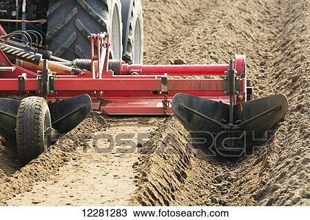 Stock Image - Making ridges for potato crop using a ridger pulled by a Massey Ferguson 7624; Yorkshire, England. Fotosearch