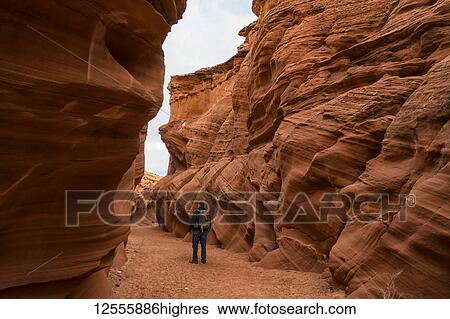 Stock Photograph - Man walking in slot canyon known as Owl Canyon, near Page; Arizona, United States of America. Fotosearch