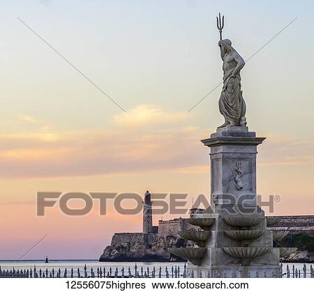 Stock Photograph - Morro Castle at sunset, with a statue of Poseidon with trident in the foreground; Havana, Cuba. Fotosearch