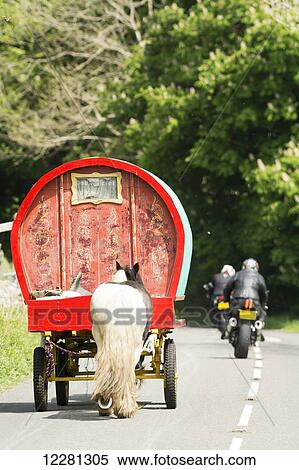 Stock Photography - Motorcyclists overtaking a horse drawn caravan on a rural road; Cumbria, England. Fotosearch