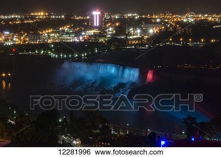 Stock Photograph - Night view of American Falls against lights of the city; Niagara Falls, New York, USA. Fotosearch