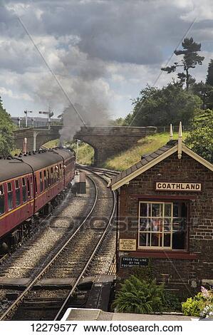 Stock Photo - Passenger train traveling by Goathland station; Goathland, Yorkshire, England. Fotosearch