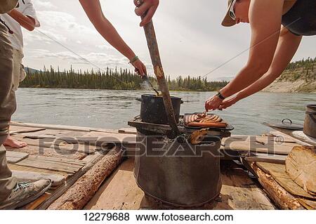 Stock Photo - People cooking a meal on a handmade raft while floating down the Yukon River, Yukon Territory, Canada. Fotosearch