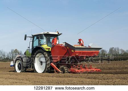 Stock Photo - Planting seed potato in freshly prepared seed bed using a Grimme seed drill pulled by a Claas ARES 816RZ tractor; Yorkshire, England. Fotosearch