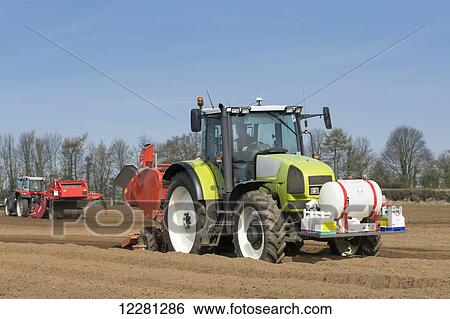 Stock Photograph - Planting seed potato in freshly prepared seed bed using a Grimme seed drill pulled by a Claas ARES 816RZ tractor; Yorkshire, England. Fotosearch